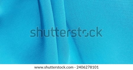 Wavy blue crepe chiffon, in vertical folds (macro, texture).
