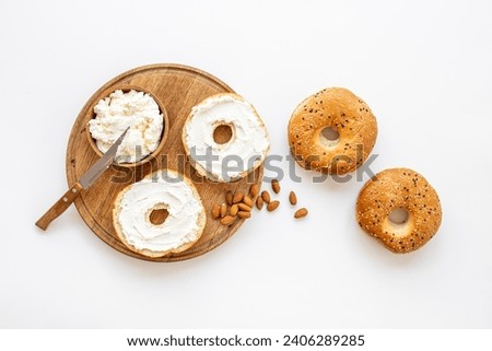 Fresh baked bagels with cream on board, top view. Healthy breakfast background. Royalty-Free Stock Photo #2406289285