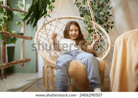 A little girl is relaxing in room with a wicker chair. A schoolgirl is lazy after school. Teen idling at home