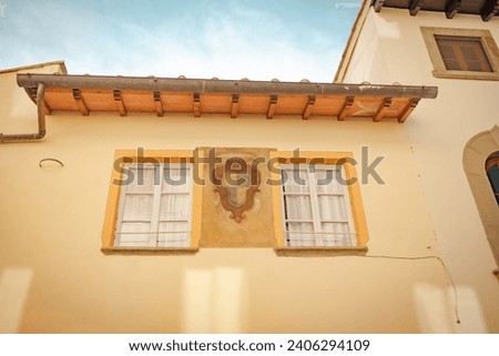 Two vintage windows on a bright orange wall. Exterior facade of historical house with apartments in Florence, Italy. Urban vintage background. High quality photo