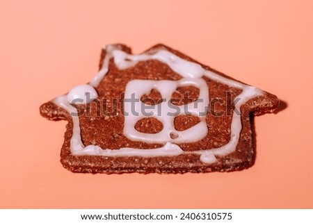 A colorful house-shaped cookie-gingerbread on a pink background. gingerbread house on a pink background. Gingerbread with a frosted surface.