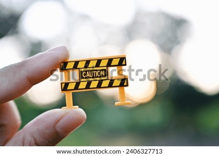 hand holding caution sign, green nature copy space background for text, planning and manage to success business concept