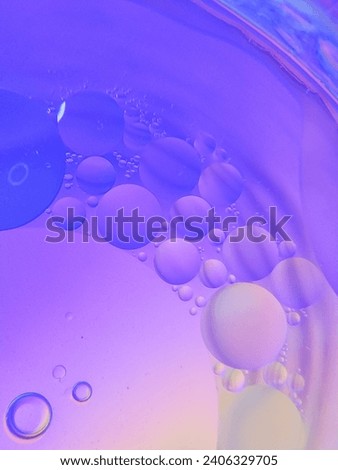 Top view of movement of oil bubbles in liquid. Fantastic colorful bubble structure. Colorful artistic image of oil droplets floating on water. Macro shot of water oil emulsion over colored background
