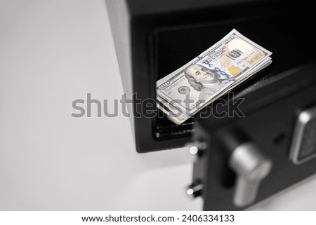 Stack of one hundred dollar bills banknotes in an open black digital steel safe box on a white isolated background. High quality photo
