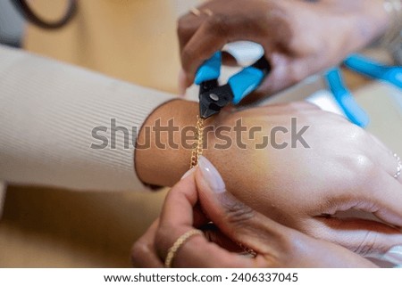 Black woman using pliers to fit jewelry on customer Royalty-Free Stock Photo #2406337045