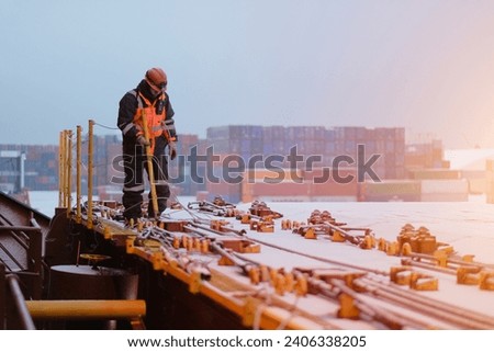 A Seafarer Walking On Deck Wearing Protective Safety Clothes and Distributing The Safety Handrails Before The Commencement Of Cargo Operations In The Port Royalty-Free Stock Photo #2406338205
