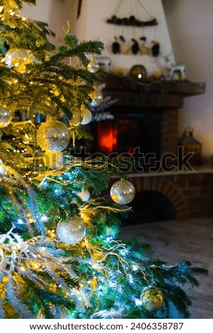 Immerse in the holiday spirit with this enchanting photo featuring baubles on a Caucasian Fir. Blurred Christmas lights and festive decor enhance the cozy atmosphere.