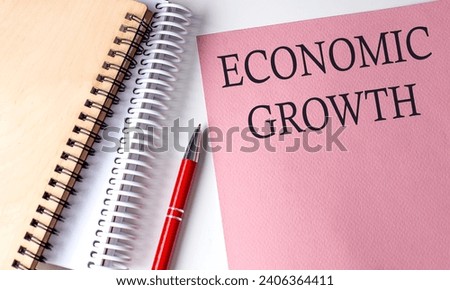 ECONOMIC GROWTH word on pink paper with office tools on white background