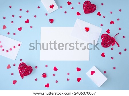 Blue background, Valentine's Day flat lay, copy space for text, holiday gifts frame, envelope and red hearts, white sheet of paper.  Concept of love, romance, close relationships