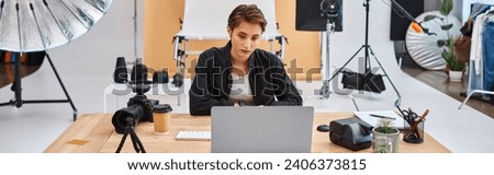 attractive female photographer in casual attire working at laptop with coffee cup on table, banner