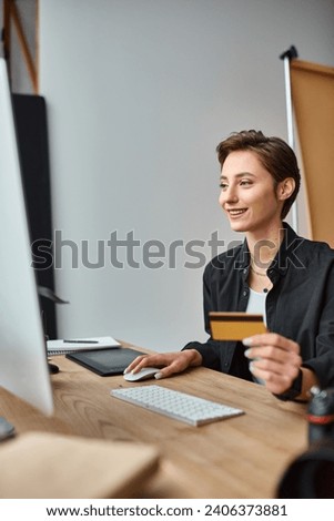 happy attractive female photographer paying online using her credit card and smiling joyfully