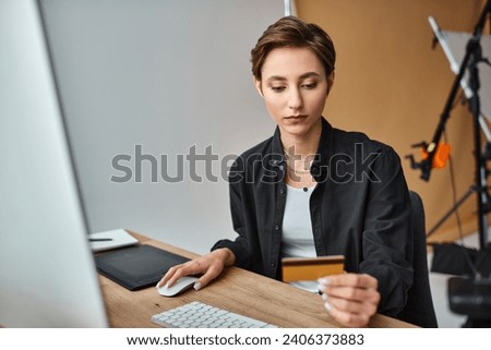 attractive young female photographer in casual comfy attire paying online with her credit card