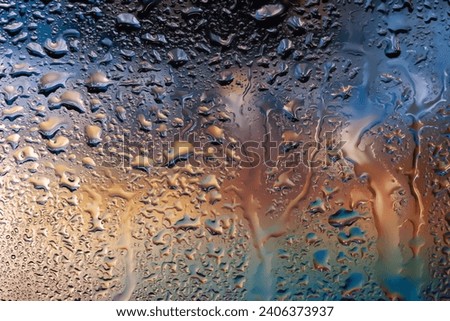 Abstract background. Water drops on glass. Raindrops on the window. Multi-colored spots. Drops texture. Soft focus