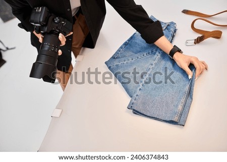 cropped view of young female photographer preparing to make object photos of denim and brown belt