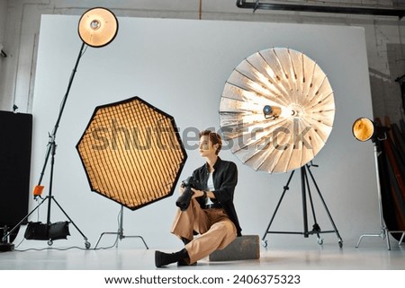 attractive young female photographer in casual clothes posing in her studio and looking away
