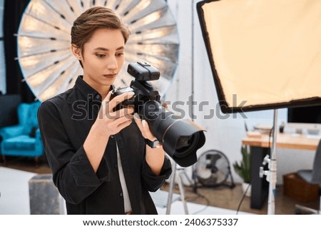 appealing concentrated woman in casual attire taking photos with her modern camera in her studio