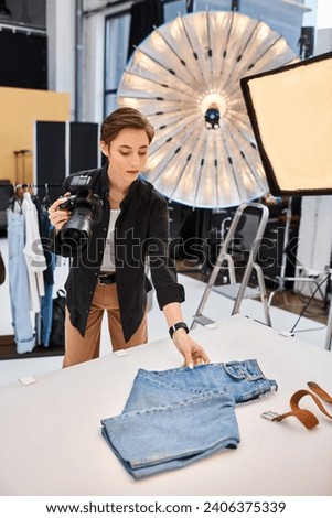 charming focused female photographer holding camera and preparing to take photos in her studio