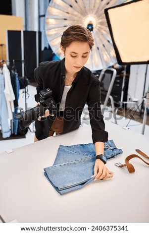 beautiful focused female photographer holding camera and preparing to take photos in her studio