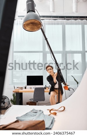 charming short haired female photographer in casual attire working with her equipment at studio