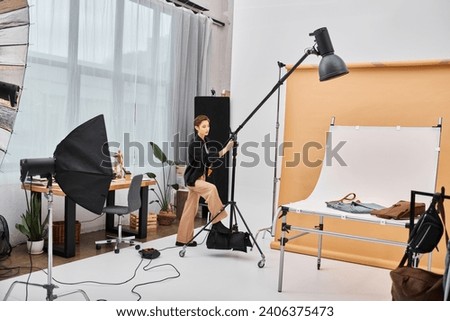 appealing short haired female photographer in casual attire working with her equipment at studio