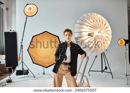 pretty short haired female photographer in casual attire looking at camera while at her studio