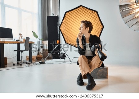 beautiful young female photographer in casual attire posing in her studio and looking away
