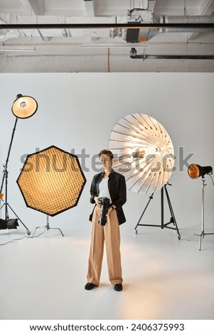 attractive female photographer in everyday outfit looking at camera surrounded by her equipment