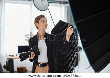 beautiful young female photographer in everyday clothes posing in her studio and looking away