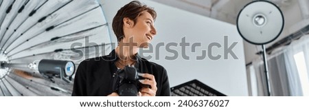 jolly female photographer in casual clothes with camera in hands smiling and looking away, banner