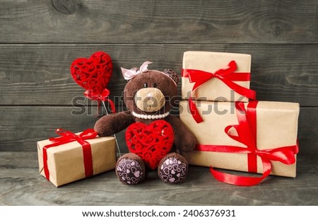 Holiday Valentine's Day.  Holiday card, on a wooden background on the table sits a cute soft toy bear with gifts and a red heart.  Symbol of friendship, love and romance.
