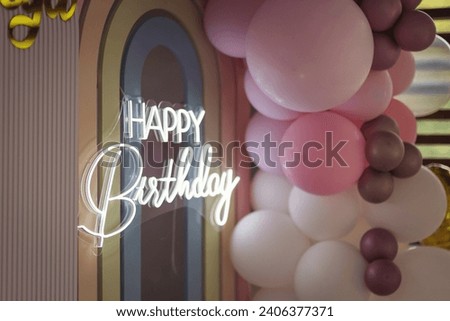 Happy birthday neon lettering sign shining between balloons. Photo zone decoration from balloons on a baby party in a restaurant. lots of gray pink balloons on holiday. birthday holiday celebration