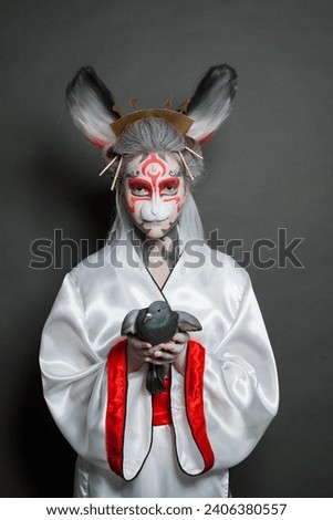 Beautiful theater actress woman with asian style makeup holding bird pigeon on black background