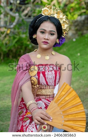 Young woman showcasing Balinese cultural dress, surrounded by greenery.