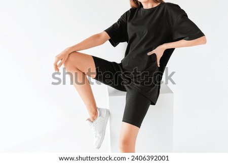A woman wears an oversized black shirt. dark streetwear outfit young girl. Girl in stylish total black outfit mock-up. Dark t-shirt on white background.