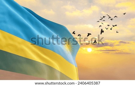 Waving flag of Rwanda against the background of a sunset or sunrise. Rwanda flag for Independence Day. The symbol of the state on wavy fabric.