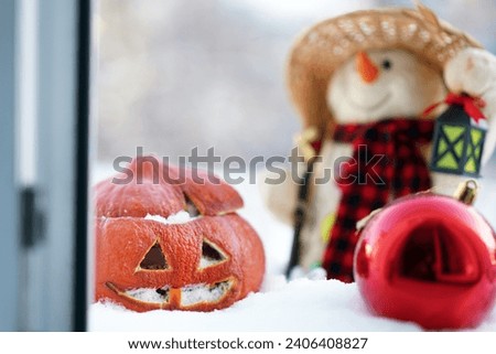 Halloween old pumpkin in snow with snowman for christmas