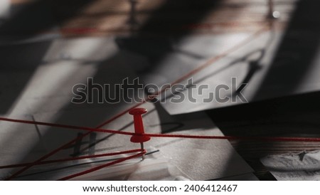 Close up shot of investigation board. Detective board with map of crime scene, pinned evidences and red thread connecting clues. Royalty-Free Stock Photo #2406412467