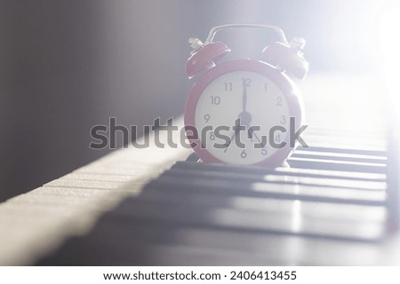 Alarm clock on piano background. Music lesson