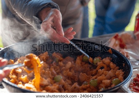 Cooking the typical Spanish dish of "Migas Castellanas" over a wood fire and you can see the entire process along with its ingredients such as bread, chistorra, peppers, garlic, bacon, grapes  Royalty-Free Stock Photo #2406421557