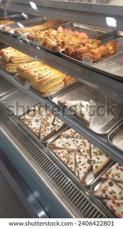 Picture to attract food lovers and specially children with lots of bakery items in show case . Mini pizzas, chicken sandwiches, different BBQ flavors are decorated with sauce and veggies looking yummy