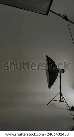 A photo studio with a white background, a table, and a variety of lighting equipment. Royalty-Free Stock Photo #2406432453