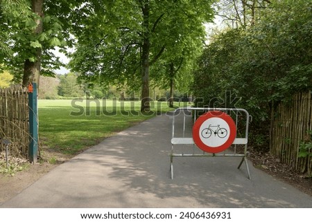 No bicycle - path only for walking. Portable fencing in a park with a warning sign - bicycle access prohibited