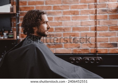 Portrait Man in barber chair. Barbershop hairdresser, brick background, warm toning.