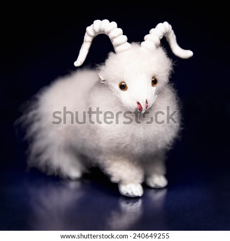 White goat or sheep toy the Chinese symbol of 2015 year on black and blue background with reflection