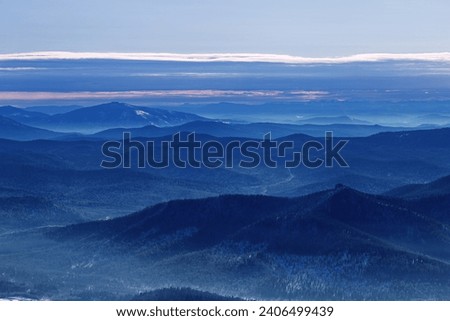 Winter nature panorama of far away blue mountains, picturesque view, aerial tonal perspective, monochrome photo of range mountains and blue sky, hills covered forest, great landscape in Altai, Russia