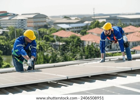 Men technicians carrying photovoltaic solar modules on the factory roof. Engineers in helmets installing solar panel systems outdoors. Concept of alternative and renewable energy.