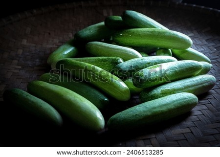 a pile of cucumbers arranged in a low light background.