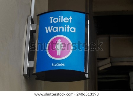 Female restroom sign "toilet wanita" on the wall.