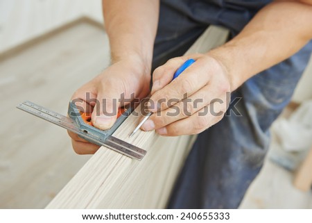 Close-up carpenter process of wood door marking for locksmith installation Royalty-Free Stock Photo #240655333