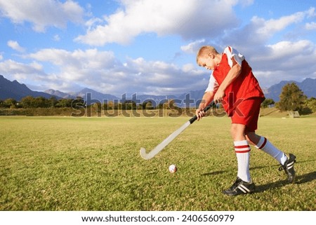 Child, ball and hockey on field for sports, outdoor practice match or game in nature. Young kid or teen player enjoying day on green grass with stick for fitness, activity or training with blue sky